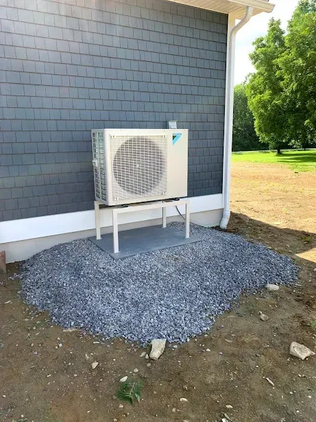 A white air conditioner is sitting on the side of a building.
