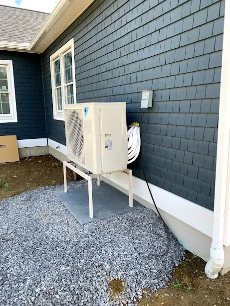 A large air conditioner is sitting on the side of a house.