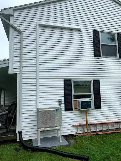 A white house with a window air conditioner on the side of it.