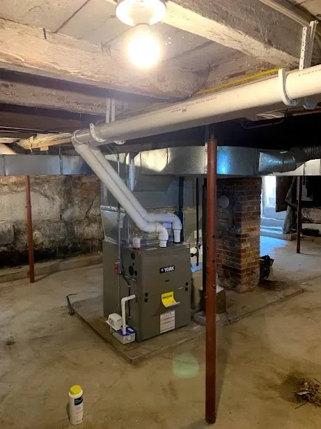 A basement with a furnace and pipes in it.