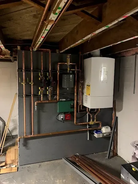 A room with a boiler and pipes on the wall.