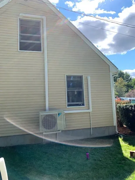 A house with a window and a fan on the side of it.