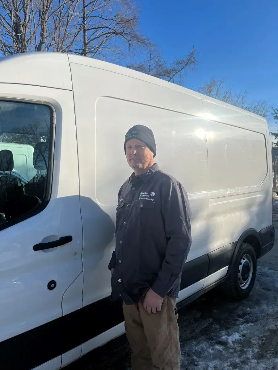 A man is standing in front of a white van in the snow.