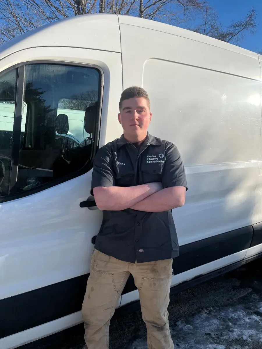 A man is standing in front of a white van with his arms crossed.