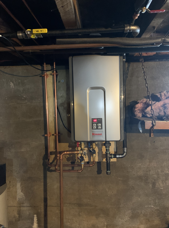 A water heater is hanging from the ceiling in a basement.