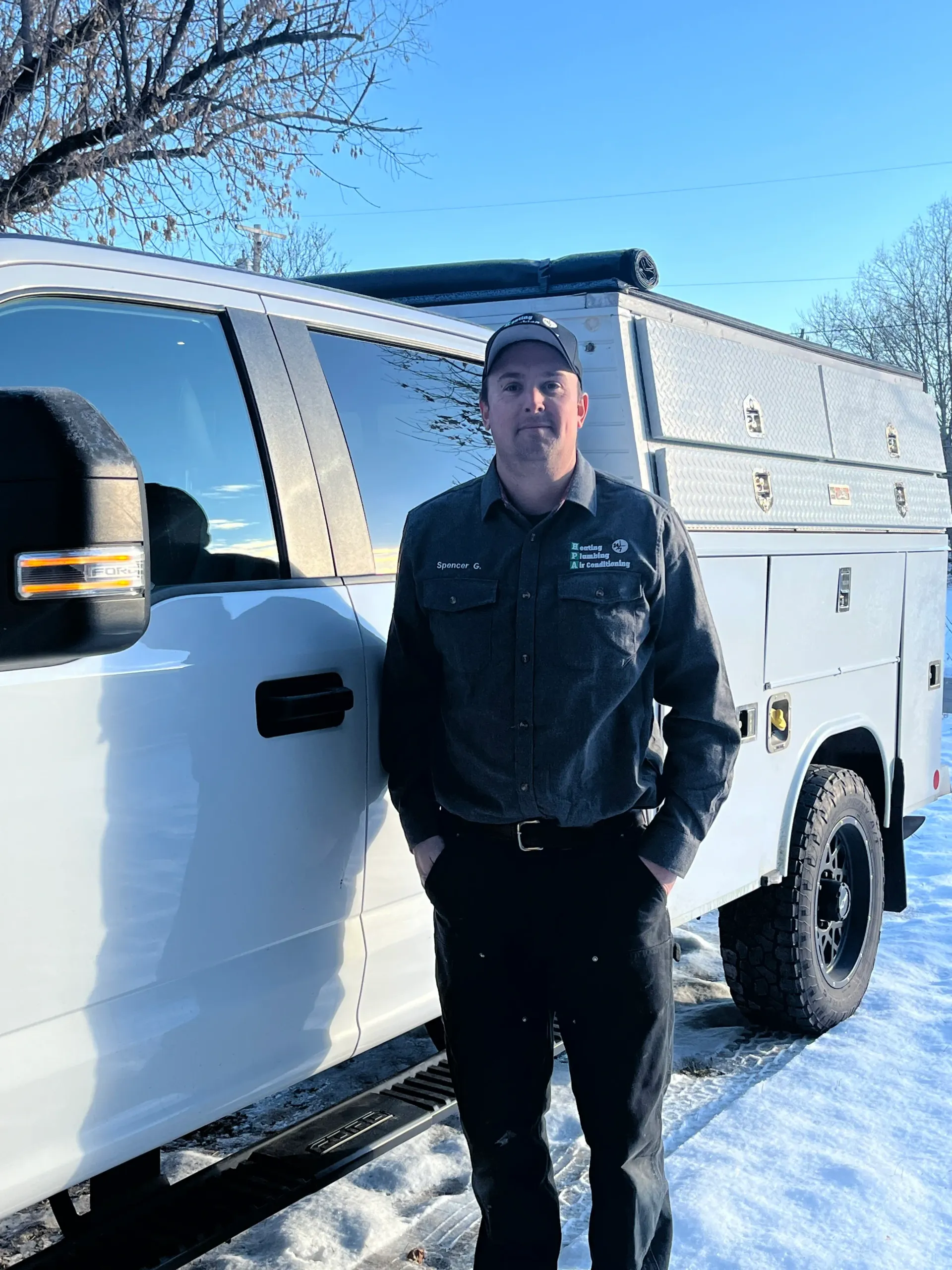 A man is standing in front of a white truck in the snow.