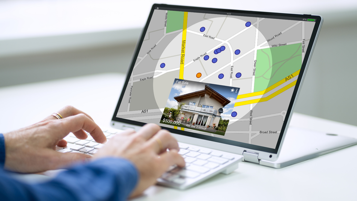 A person is typing on a laptop computer with a map on the screen.