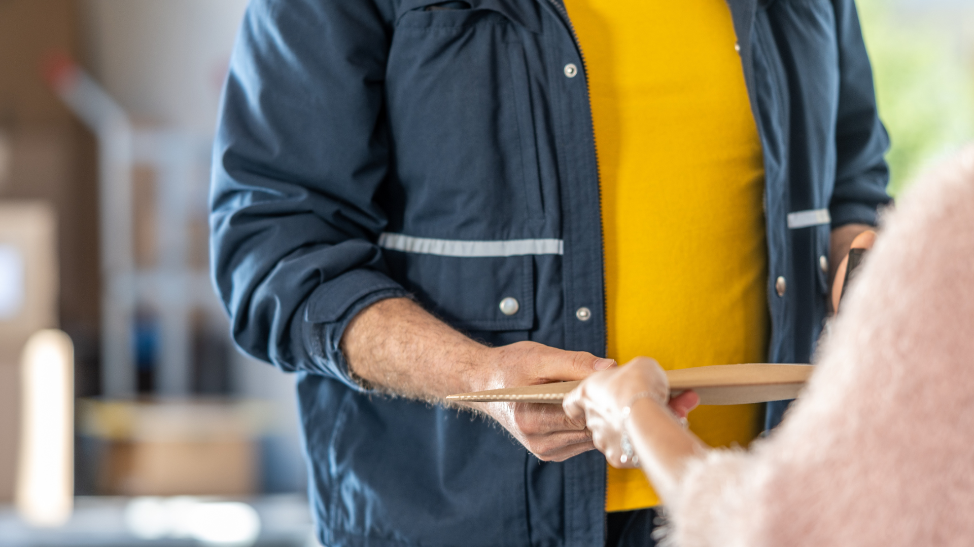 A delivery man is handing a package to a woman.