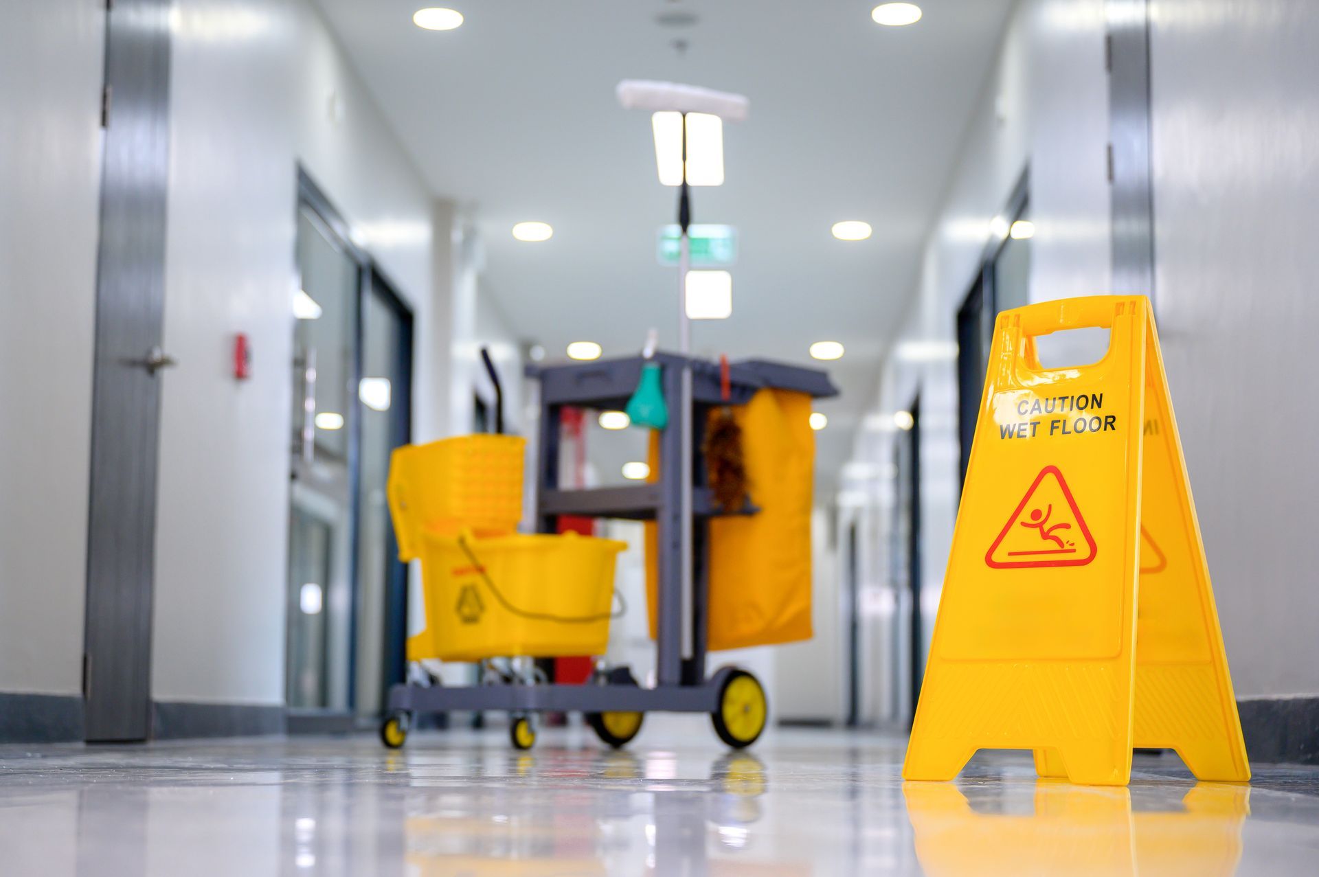 Bright hallway with janitorial cart, mop, and caution sign ensuring safety and cleanliness.