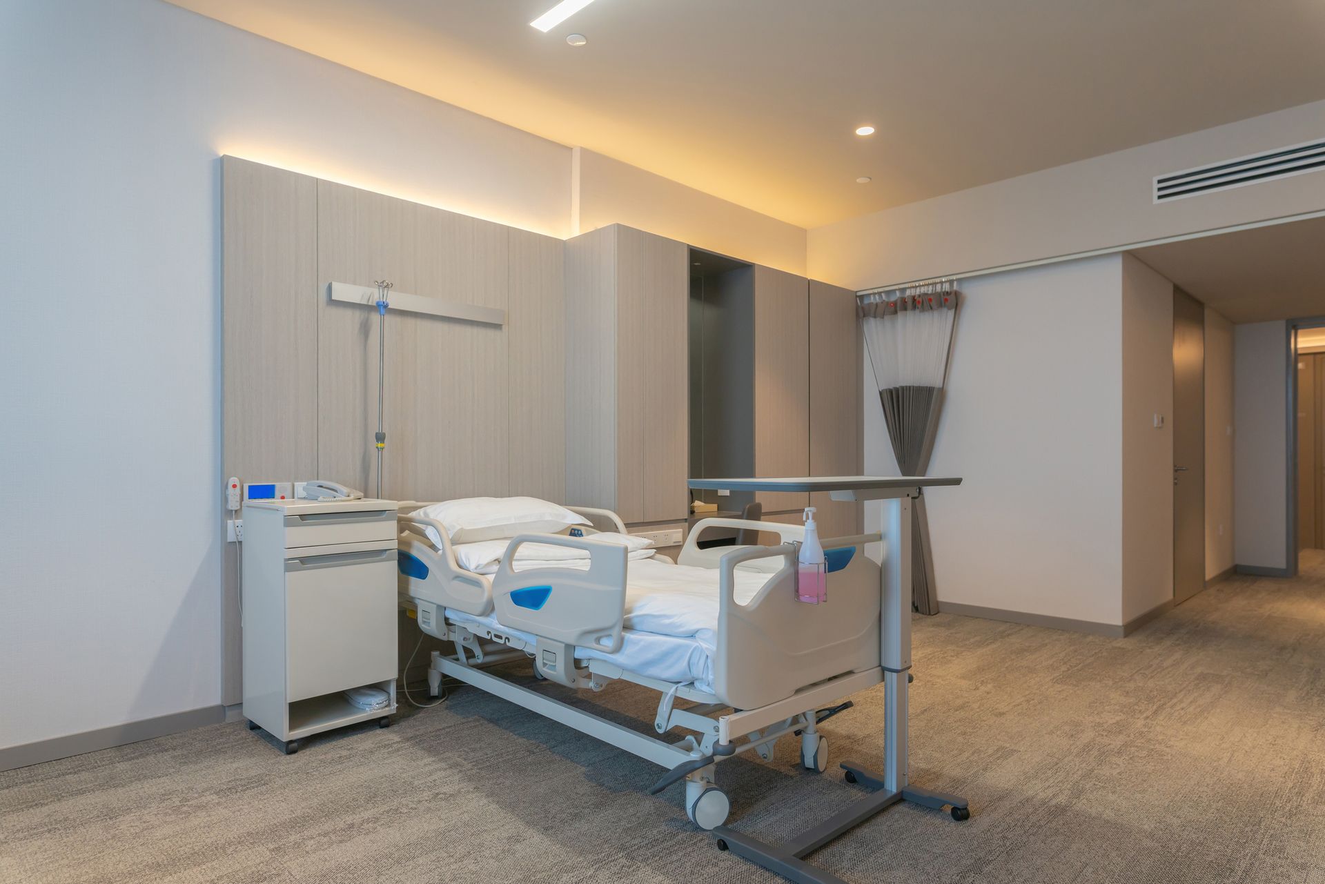 Hospital room with a bed, medical equipment, and neutral-toned walls and flooring.