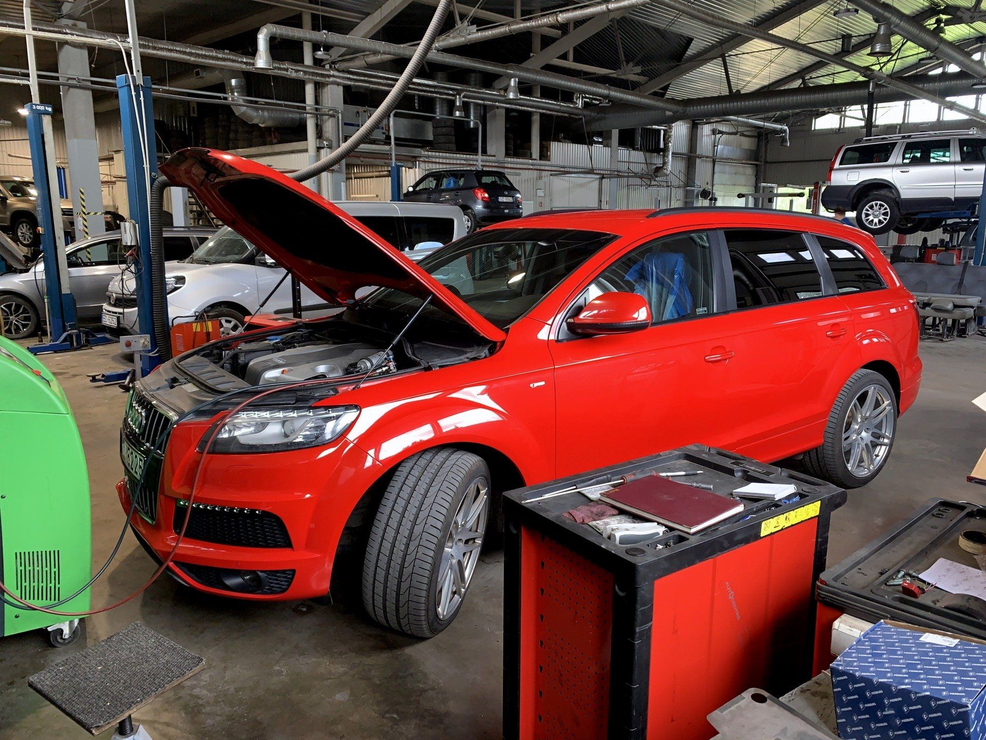 Sarkana mašīna ar atvērtu motora pārsegu garāžā