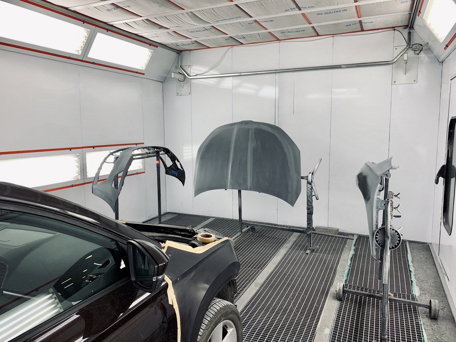 Krāsošanas kabīnē tiek krāsota automašīna.