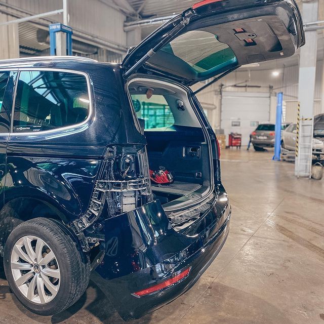 Melna mašīna ar atvērtu bagāžnieku garāžā