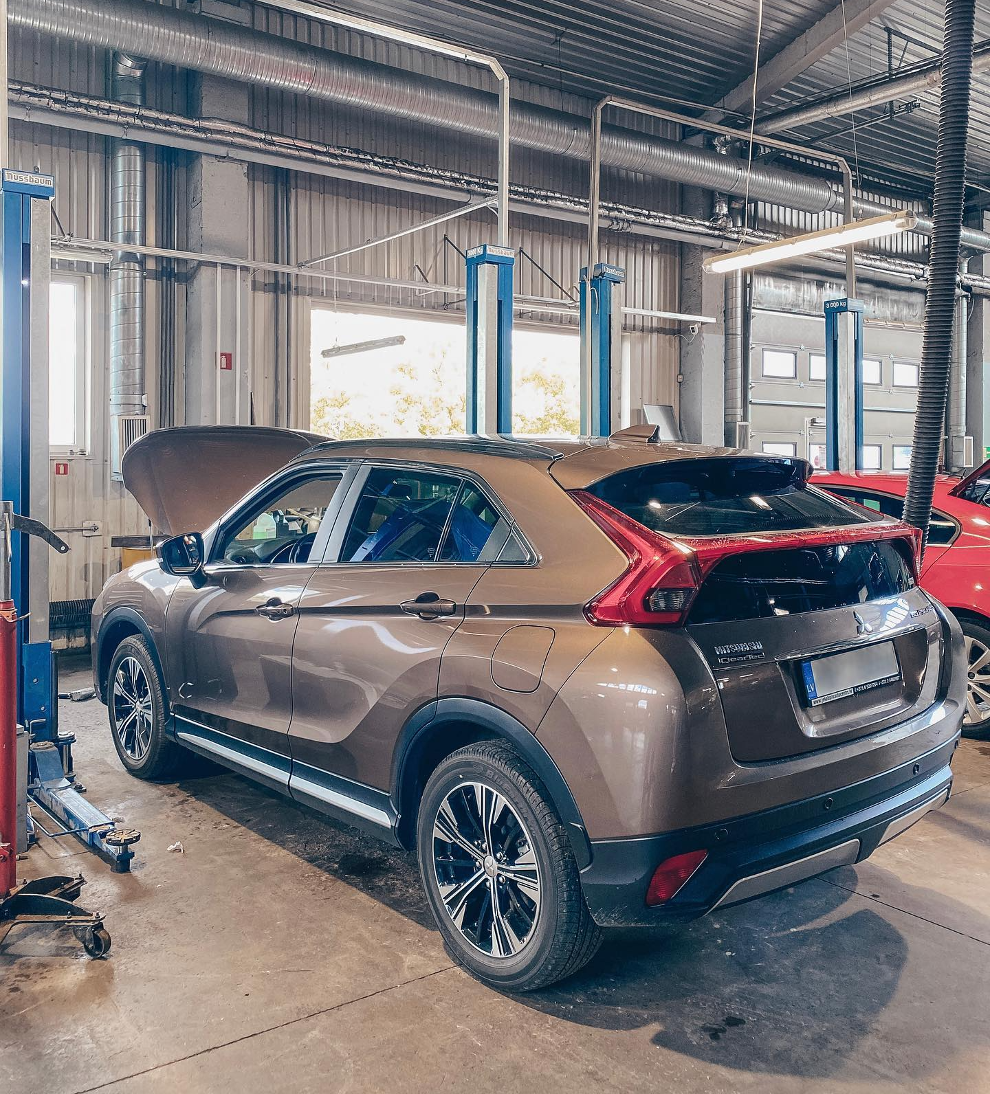 Auto ar paceltu motora pārsegu stāv garāžā.