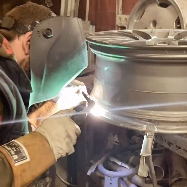 Vīrietis, kurš valkā metināšanas masku, metina riteni