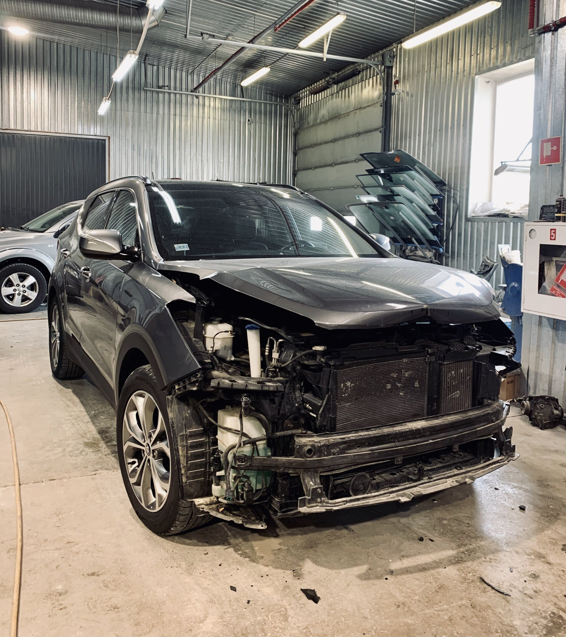 Bojāta automašīna ir novietota garāžā.