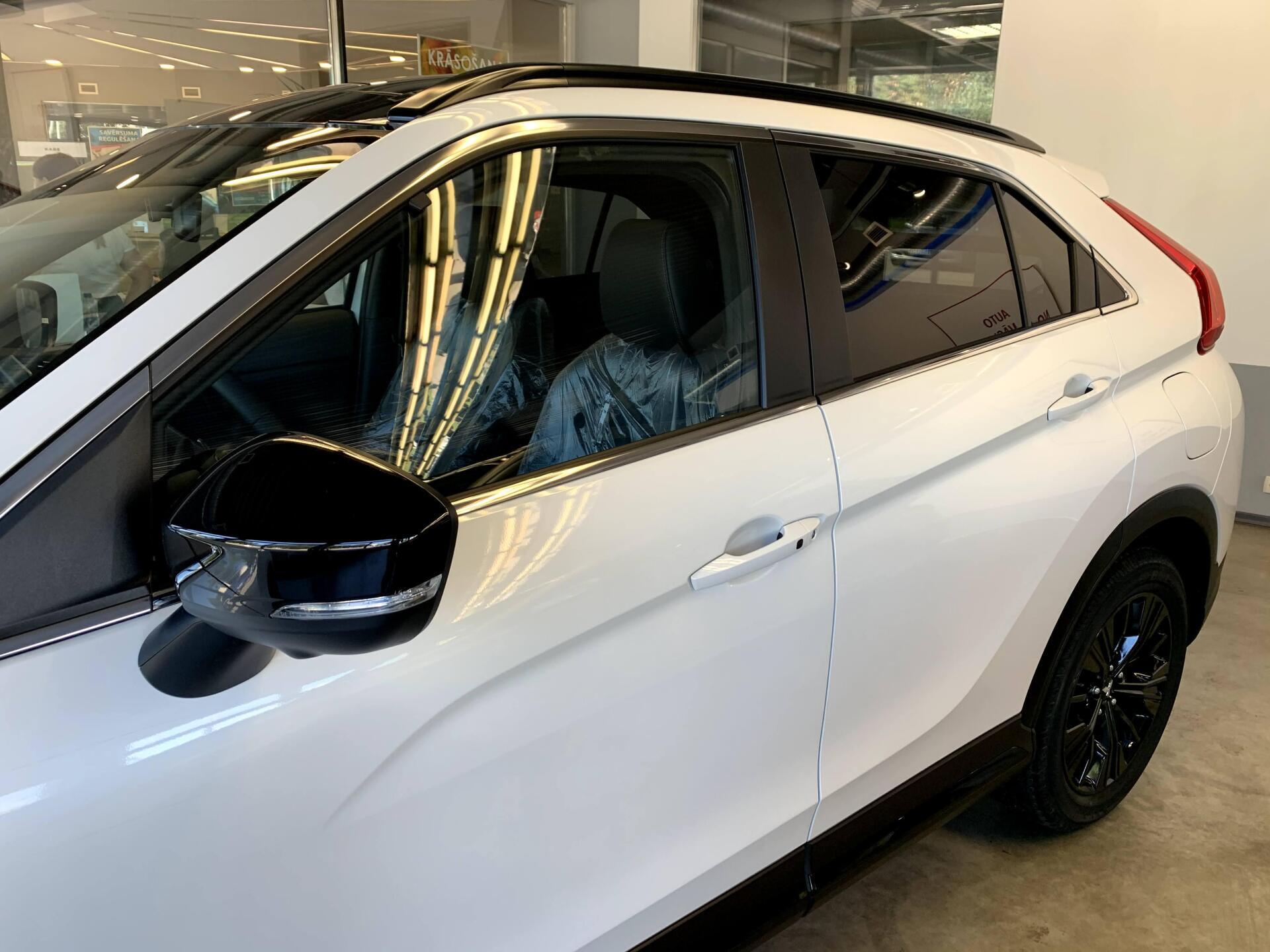 Balts mitsubishi aptumsuma krusts ir novietots izstāžu zālē.