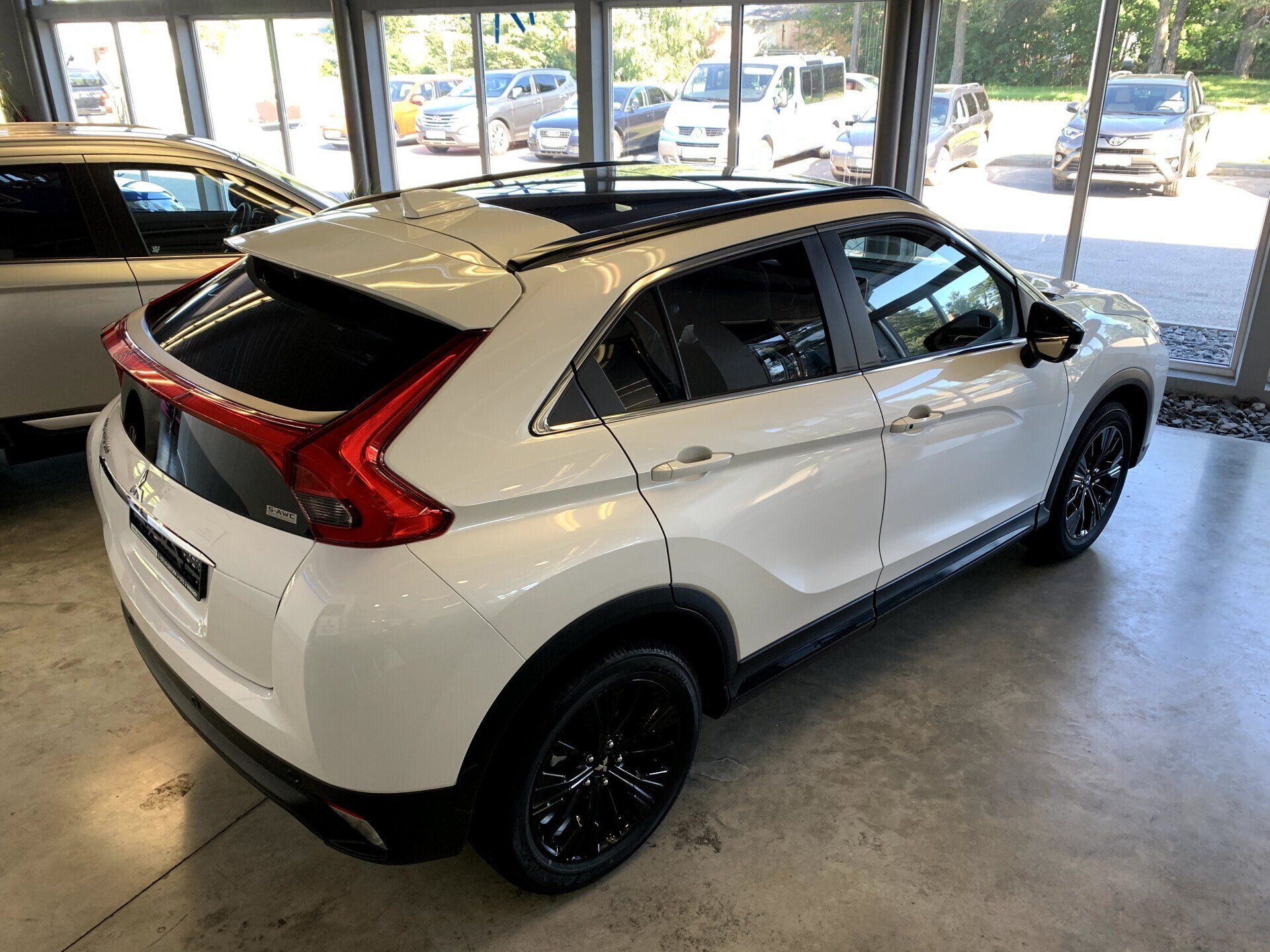 Balts mitsubishi aptumsuma krusts ir novietots izstāžu zālē.