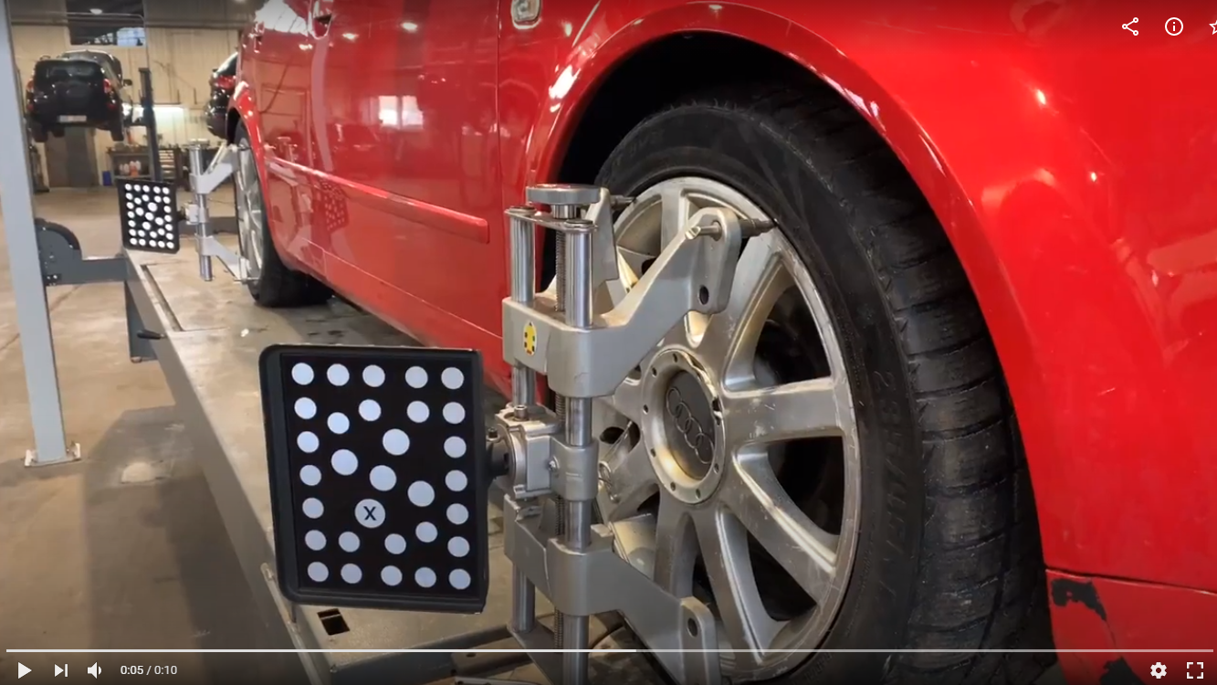 Sarkanu auto garāžā regulē mašīna.