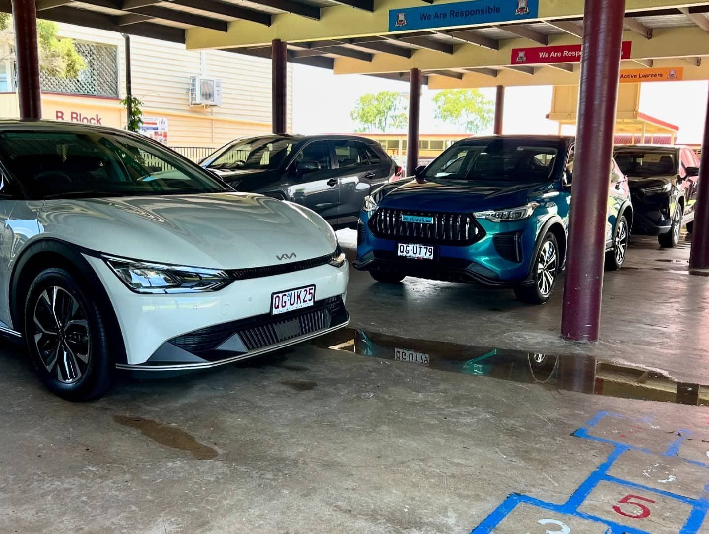 A White Car Is Parked Next To A Blue Car In A Parking Lot — Fraser Coast Automotive Coatings in Dundowran, QLD