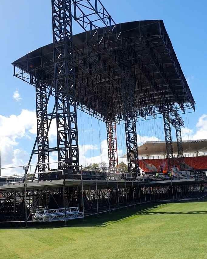 A large stage is being built in a grassy field