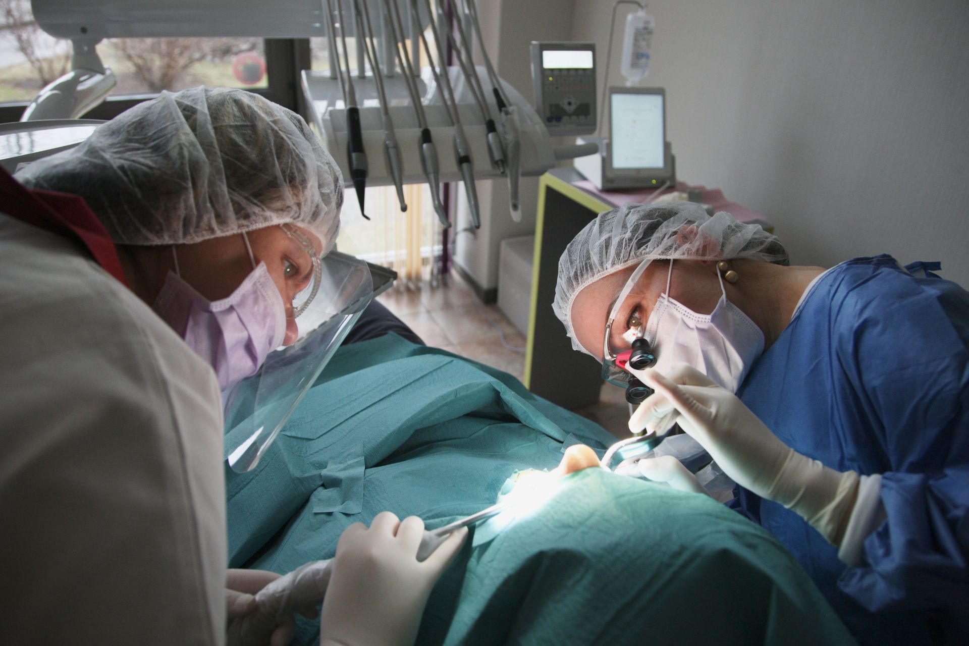 Medical team performing a surgical procedure under bright operating lights inside a sterile hospital