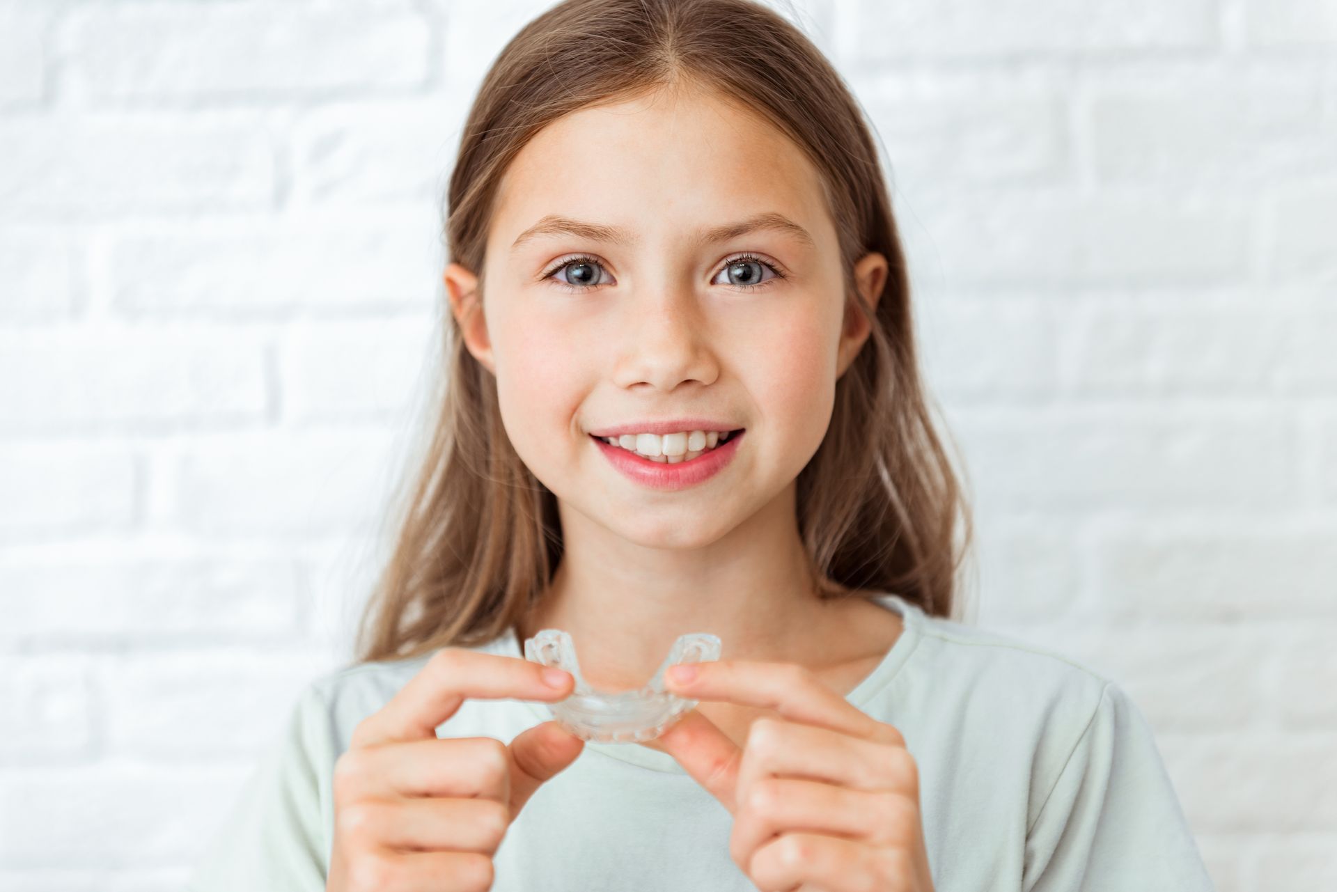 Young girl happily showing her Invisalign aligners. Young girl happily showing her Invisalign aligners.