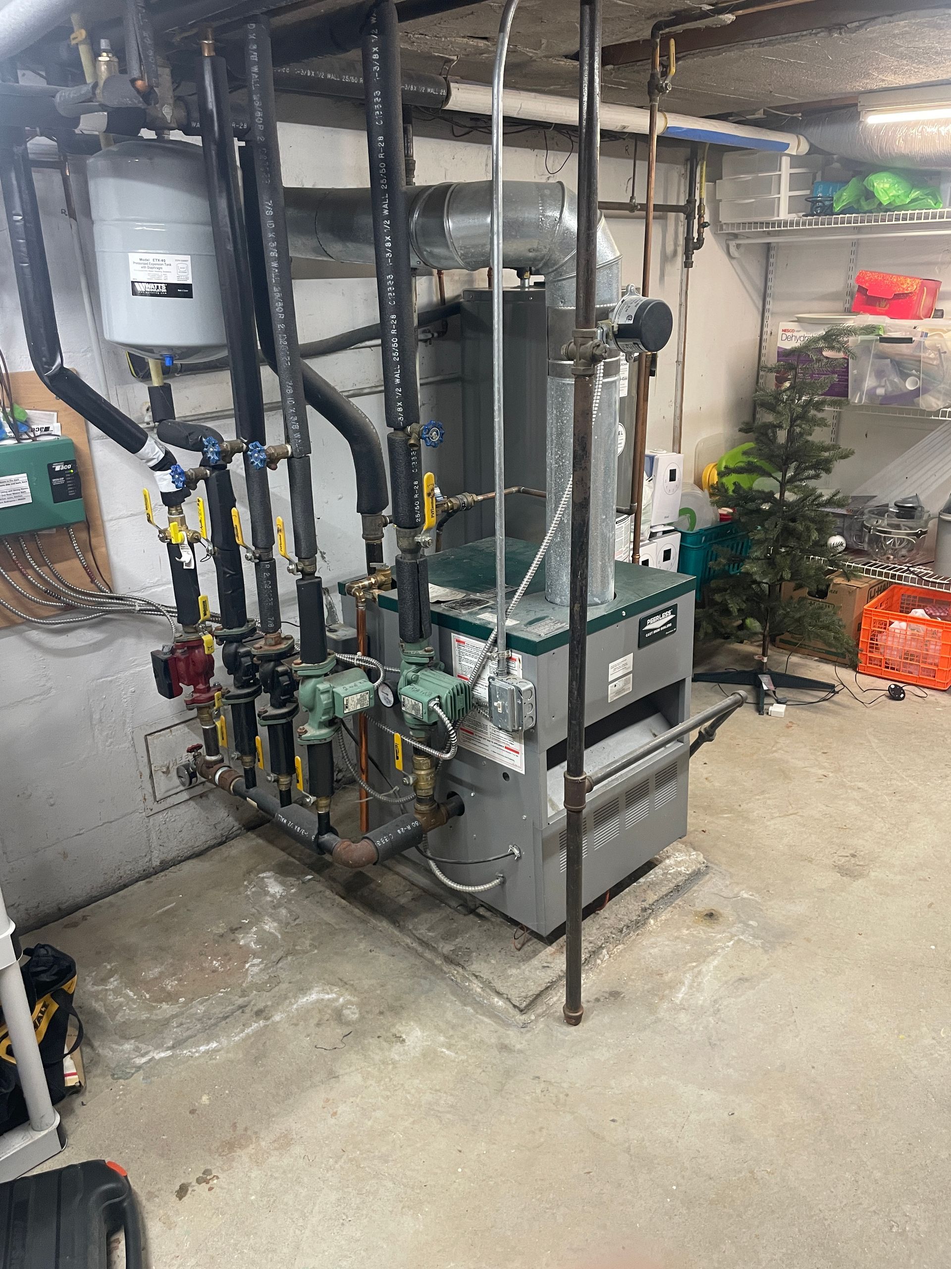 Basement boiler and plumbing equipment with pipes, valves, and utility tanks in a utility room