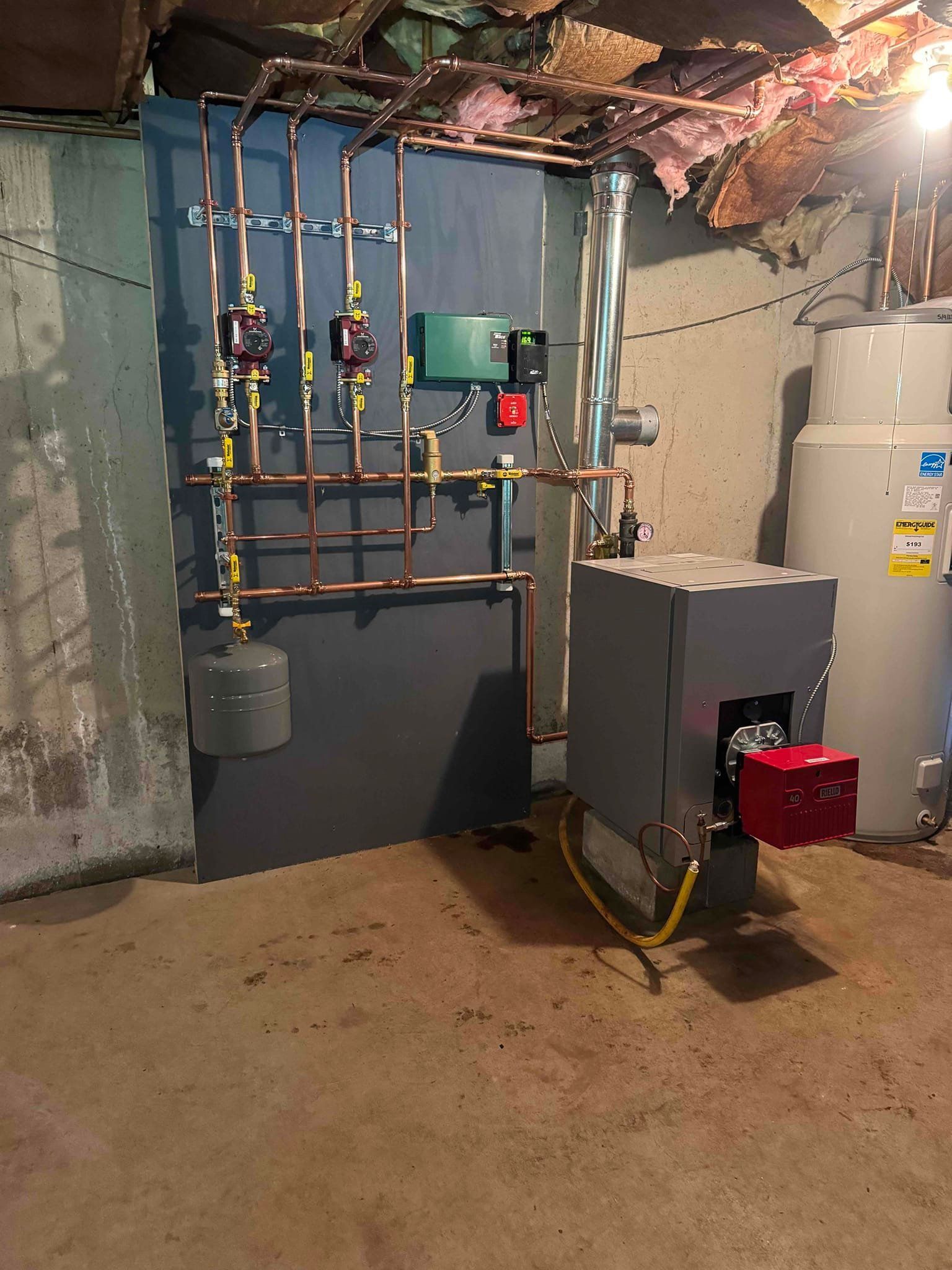 Basement utility room with water heater, furnace, exposed copper pipes, and electrical panel.
