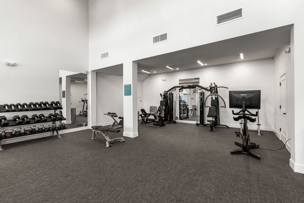Gym interior with weights, machines, mirrors, and a stationary bike.