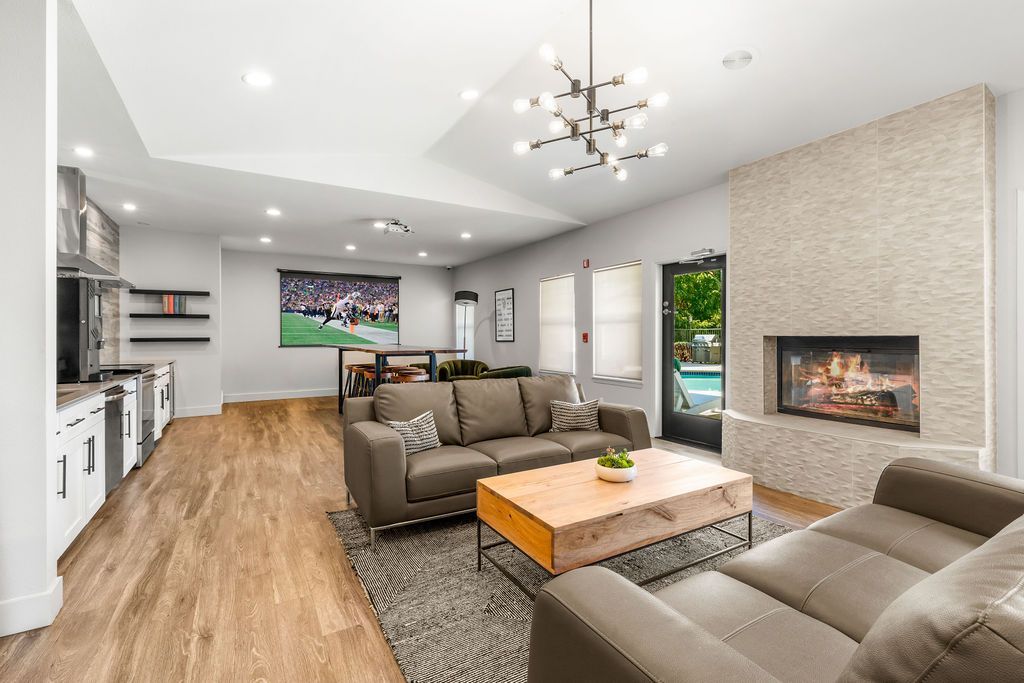Spacious living room with fireplace, brown sofa, and wooden floor; a window looks out to a pool.