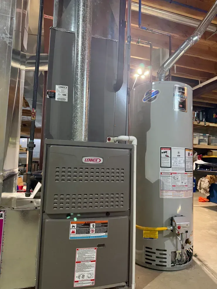 Furnace and water heater in a utility room. Gray Lennox furnace, gray water heater, silver ductwork.