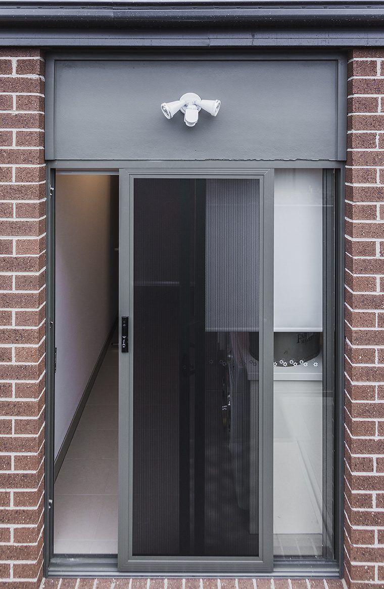 A Brick Building With A Sliding Glass Door And A Light Above It — Eastcoast Aluminium & Glass In Ballina, NSW