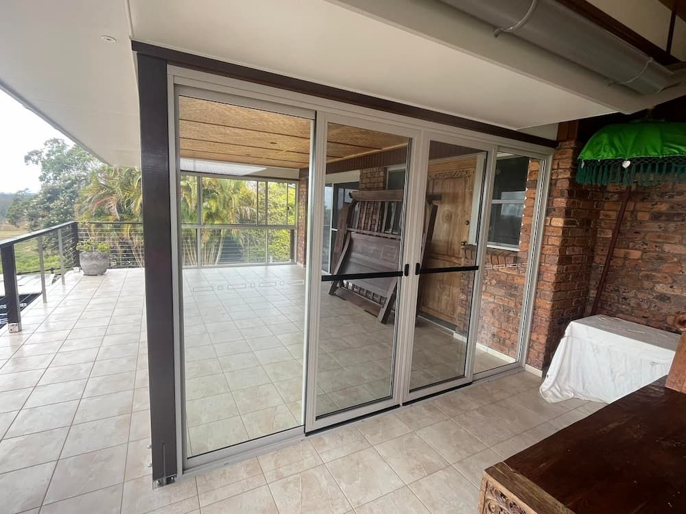 Spacious Tiled Patio With Large Sliding Glass Doors, Overlooking Lush Greenery