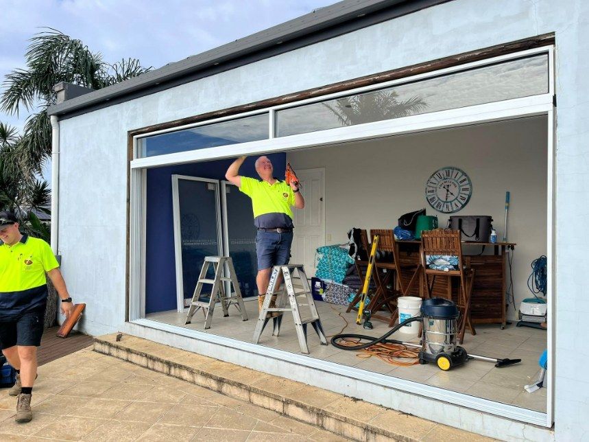 Two Workers Installing a Large Sliding Glass Door — Eastcoast Aluminium & Glass In Ballina, NSW