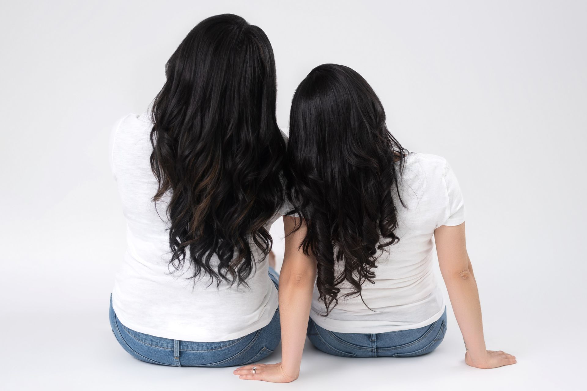 two ladies sitting with their back showing their long black hair
