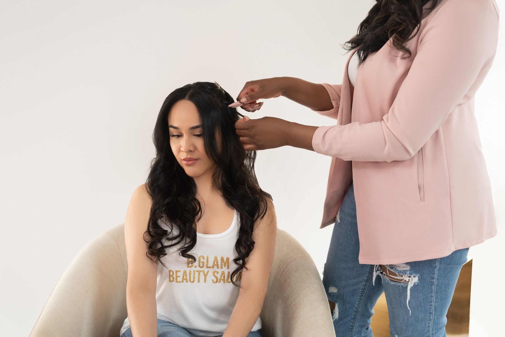 a lady wearing a white tank top getting her hair done by a professional stylist