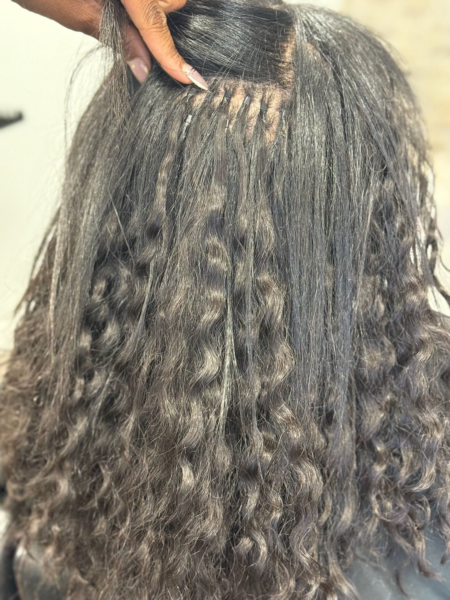 an image of a person getting i tip hair extensions in a hair salon.
