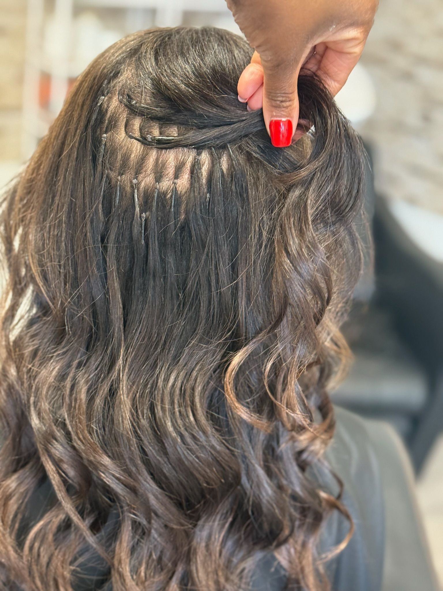 an image of a person getting brown nano extensions in a hair salon.