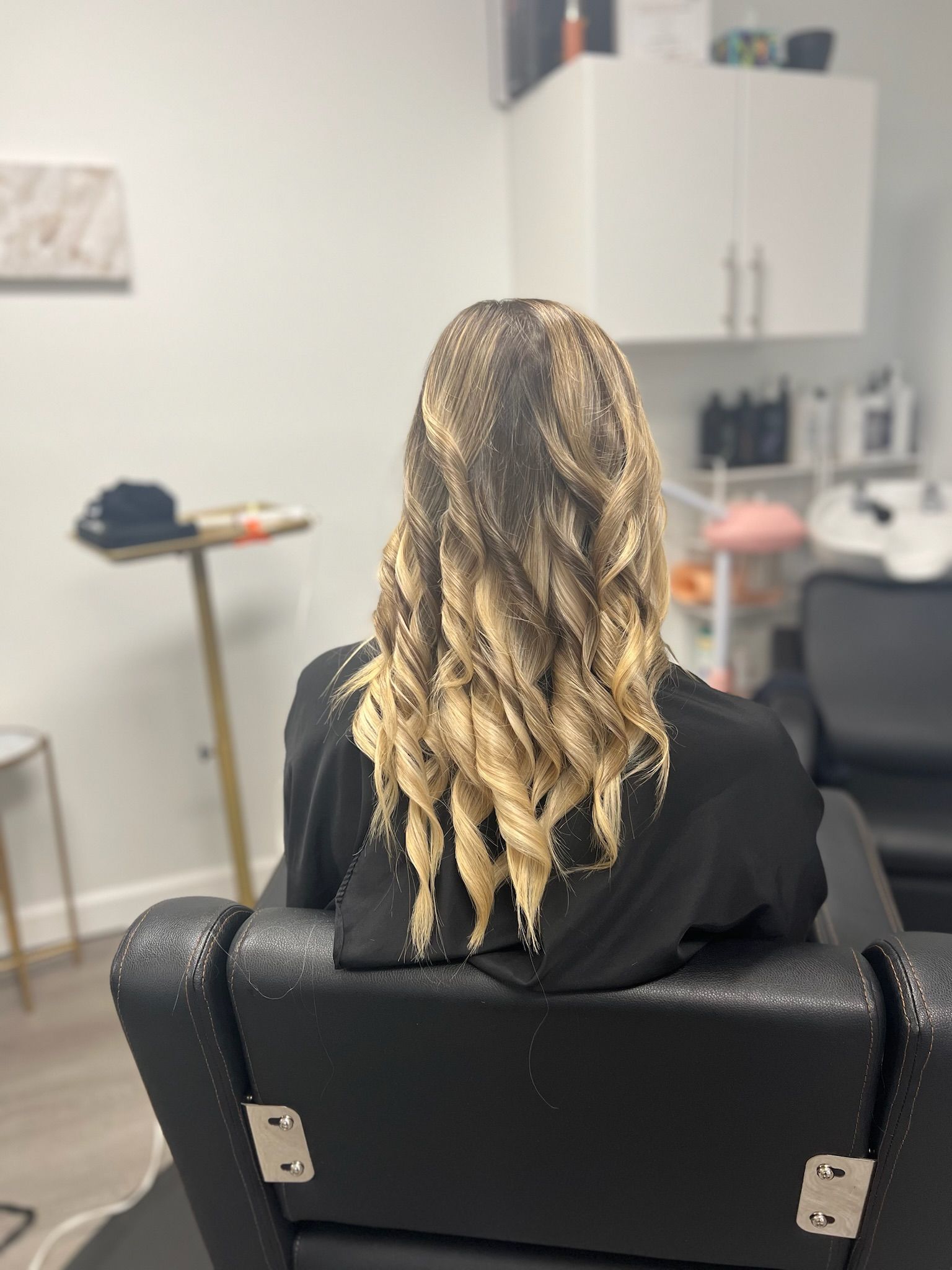 a lady in a beautiful salon sitting in the chair showing her brown and blond highlights
