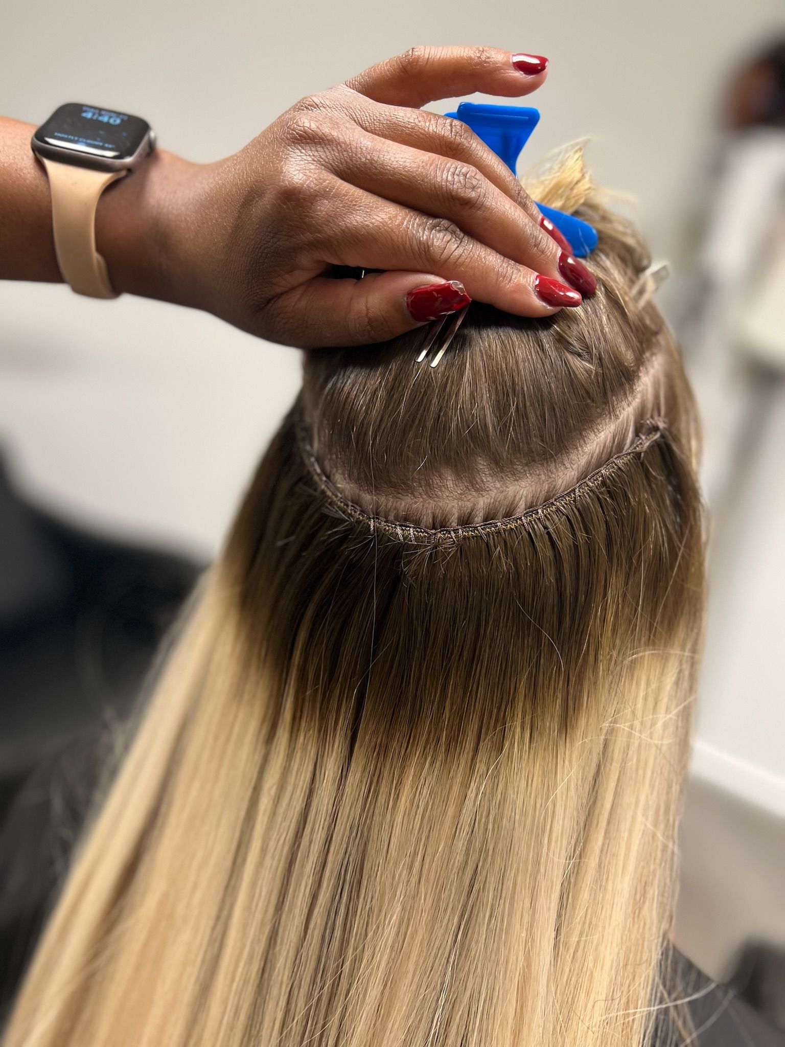 an image of a person getting blond ombre weft hair extensions in a hair salon.