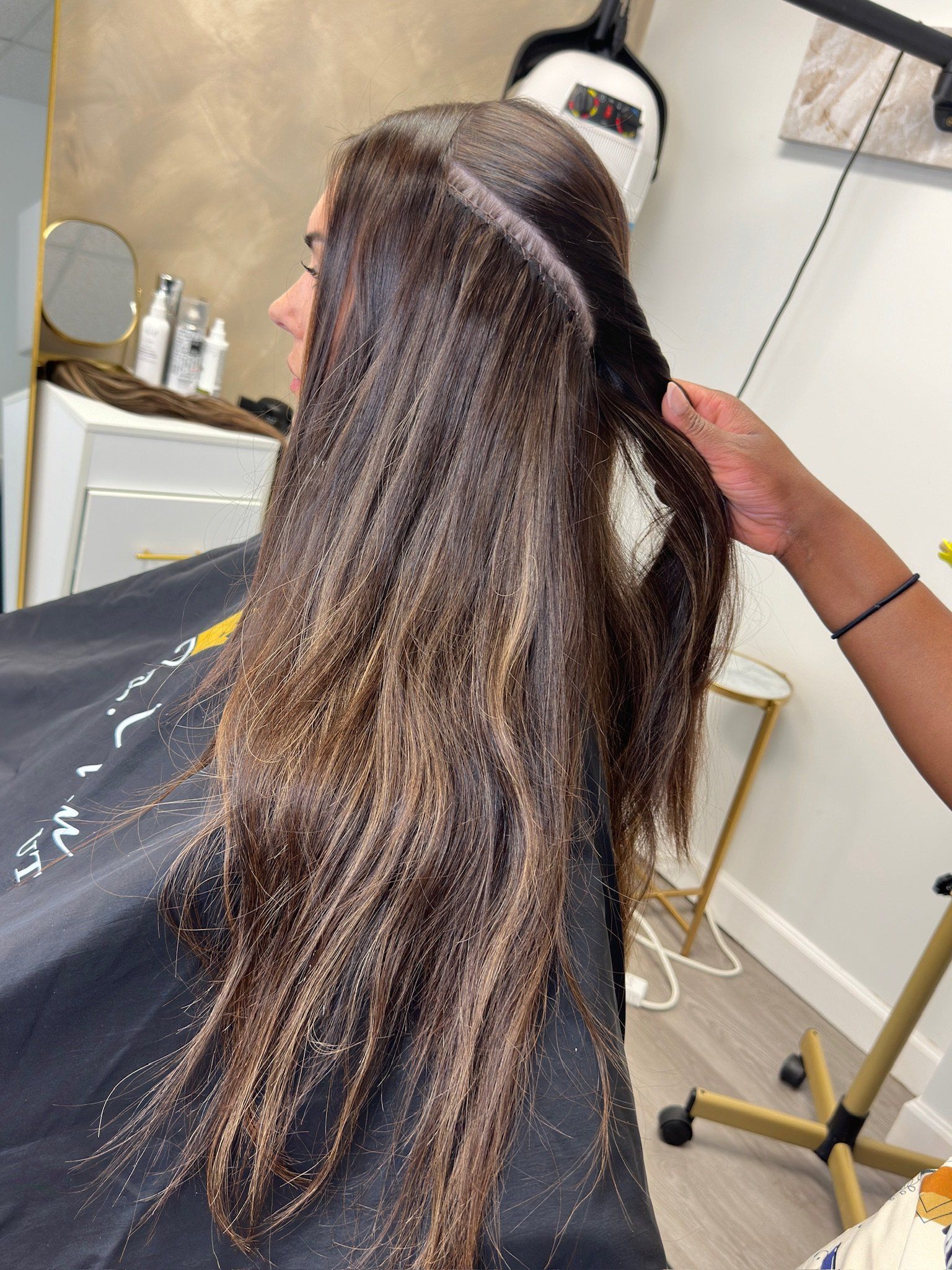 a lady in a salon with long hair getting extensions
