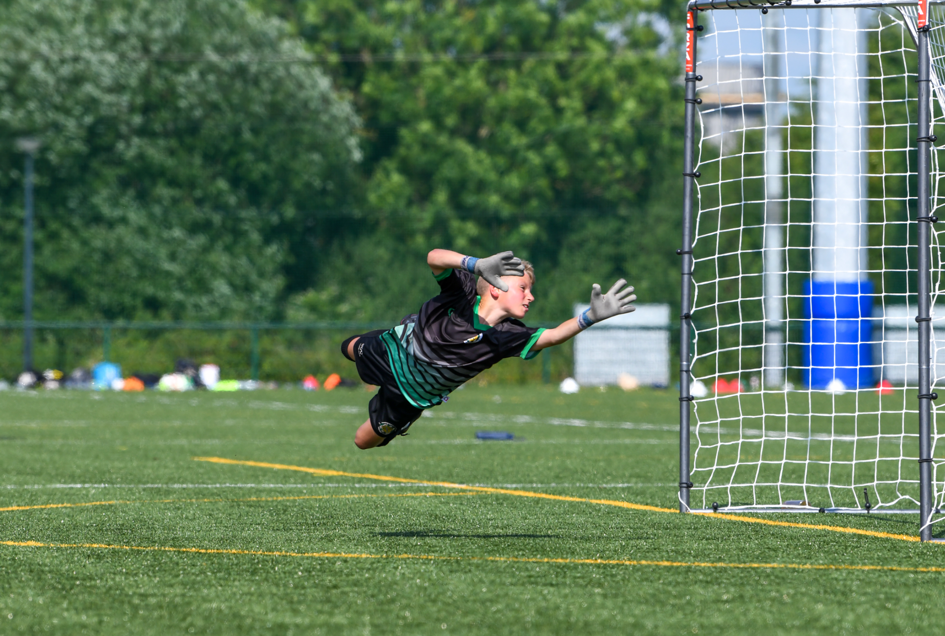 A soccer goalie is jumping in the air to catch a soccer ball.
