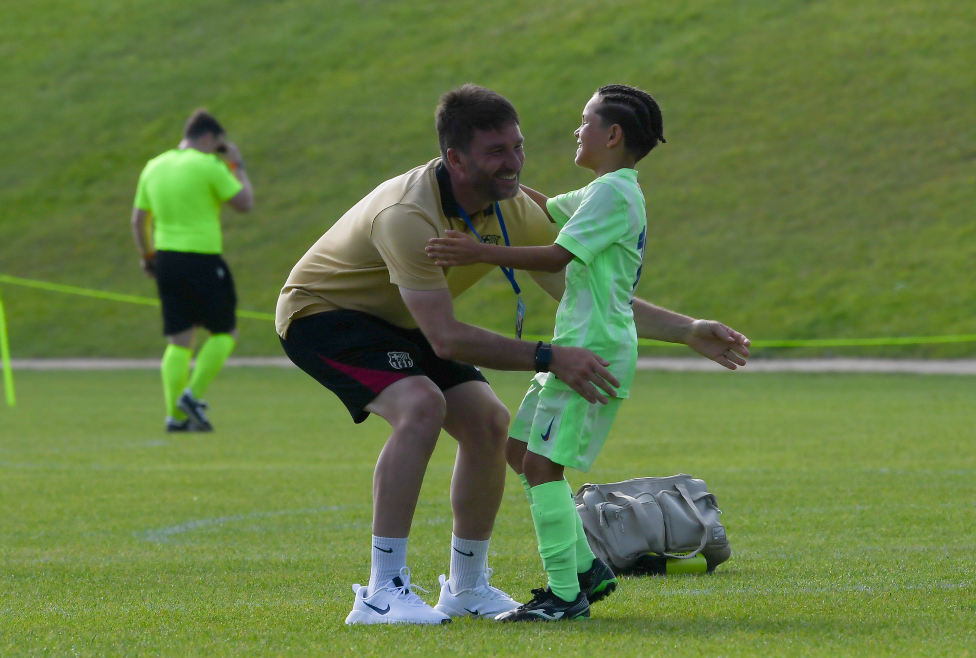 A man is hugging a young boy on a soccer field.