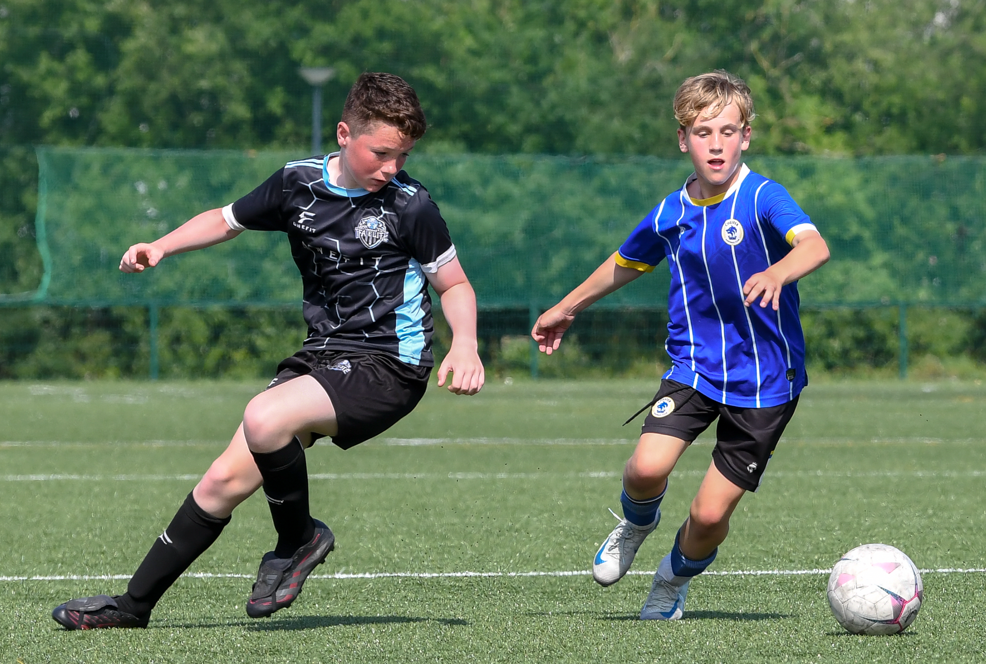 Two young boys are playing soccer on a field.