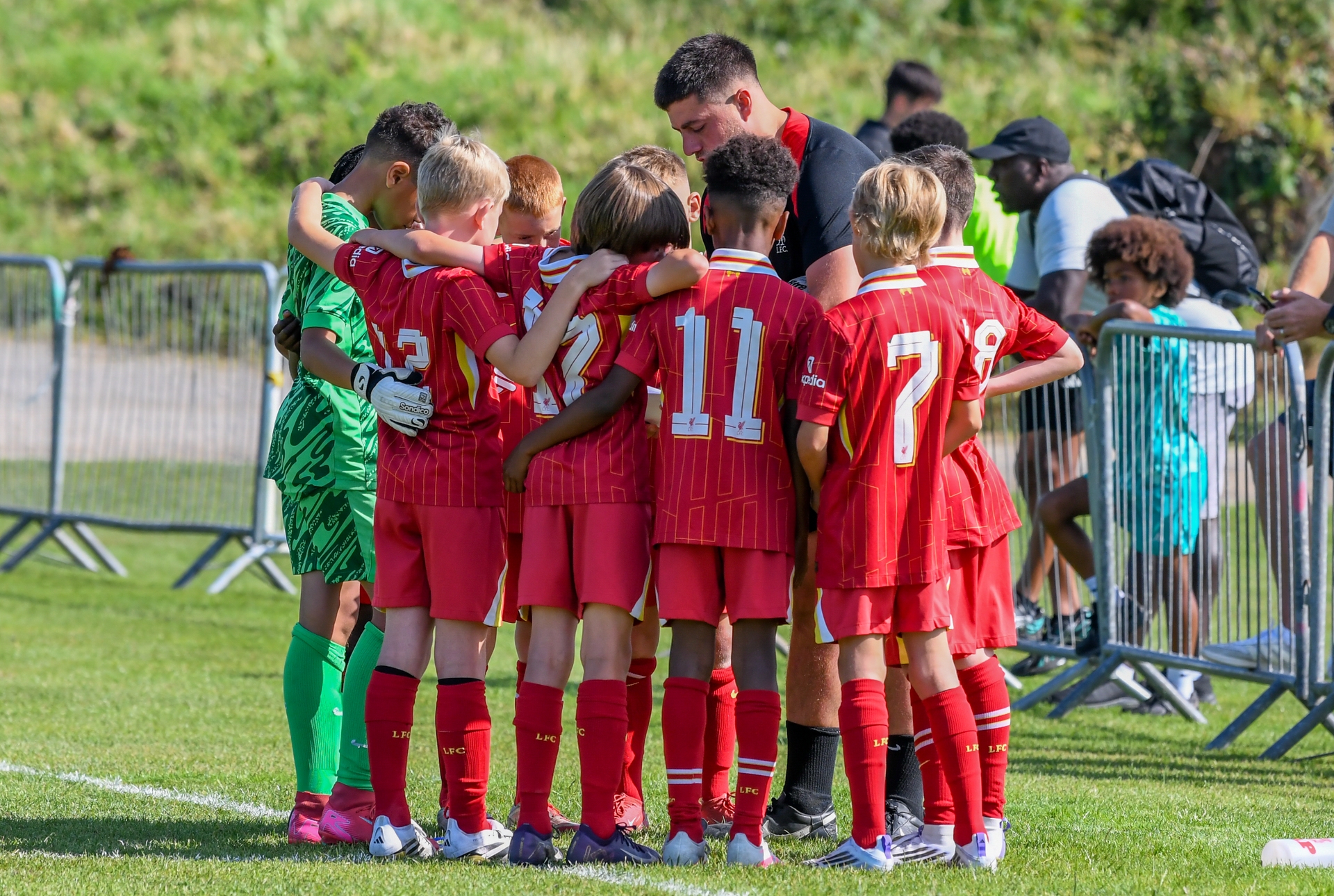 A group of young boys are huddled together on a soccer field.