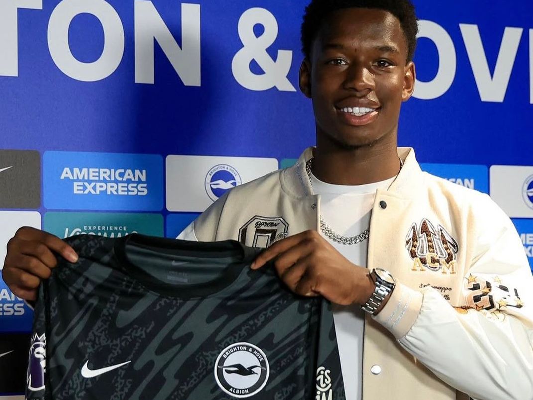 A man is holding a nike shirt in front of an american express sign