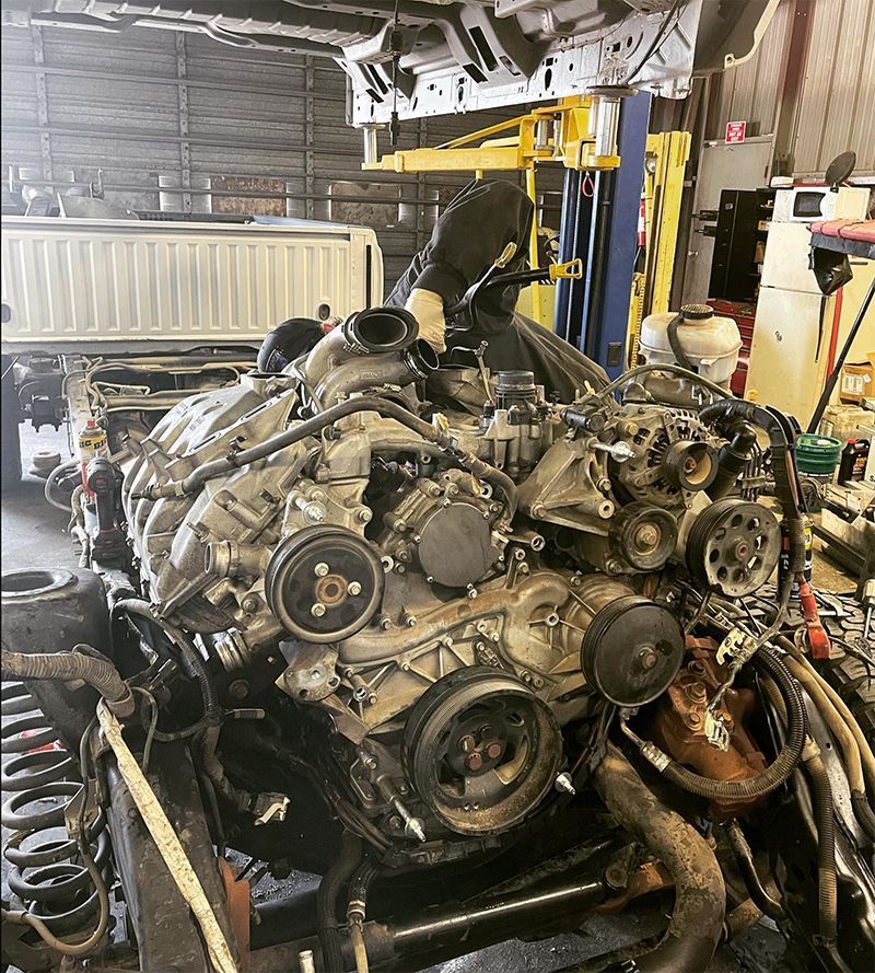 Engine being worked on in a repair shop. Black-hooded person working on the engine.