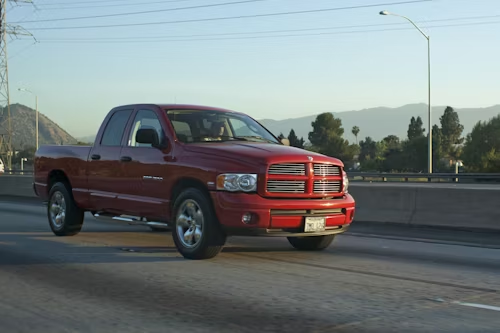 Red pickup truck driving on a highway at sunset.