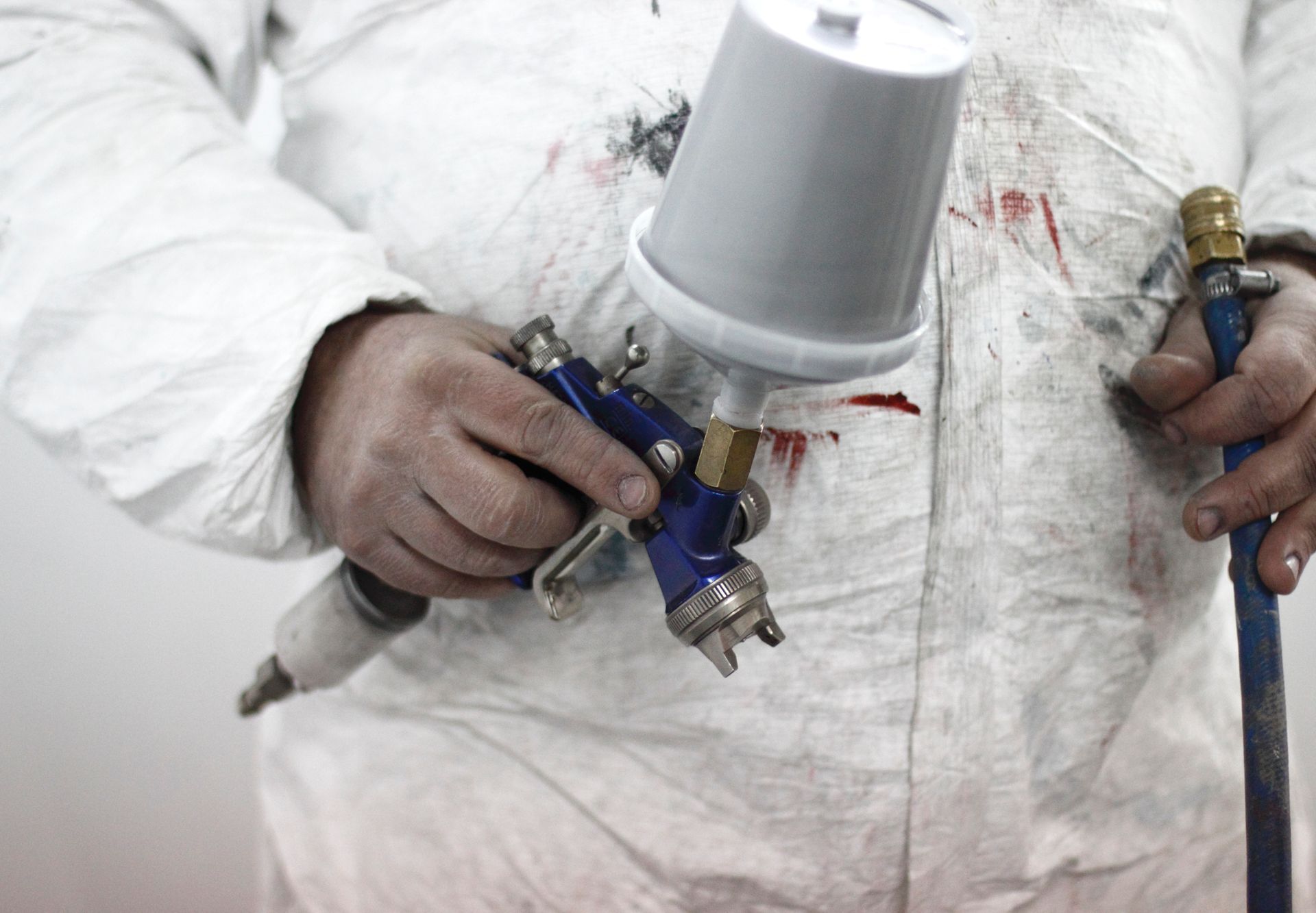 Person in paint suit holding a spray gun.